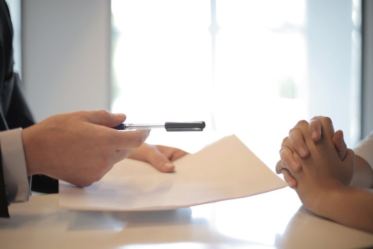 개인회생 직접하기 Close-up of a contract signing with hands over documents. Professional business interaction.